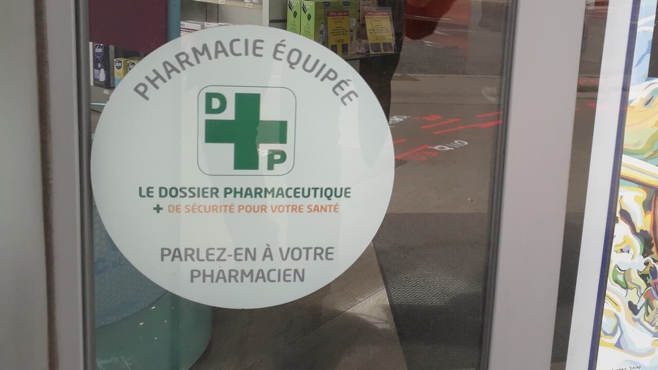 vitrine d'une pharmacie avec un autocollant indiquant que la pharmacie est connectée au système du dossier pharmaceutique