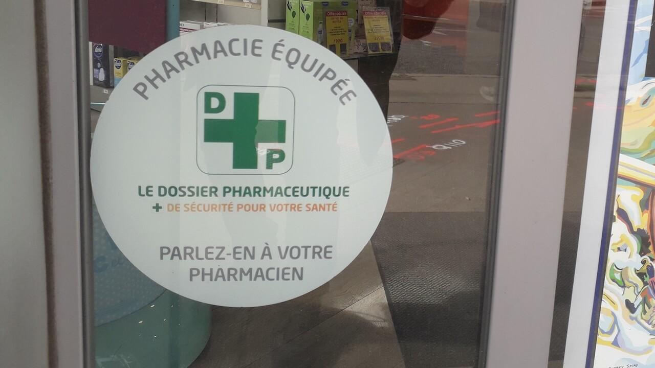 vitrine d'une pharmacie avec un autocollant indiquant que la pharmacie est connectée au système du dossier pharmaceutique